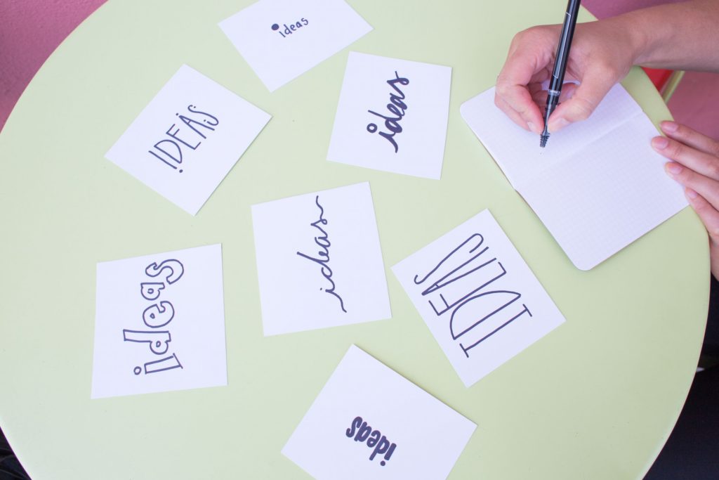 Round table covered with pieces of paper with the word "Ideas" written in various fonts.